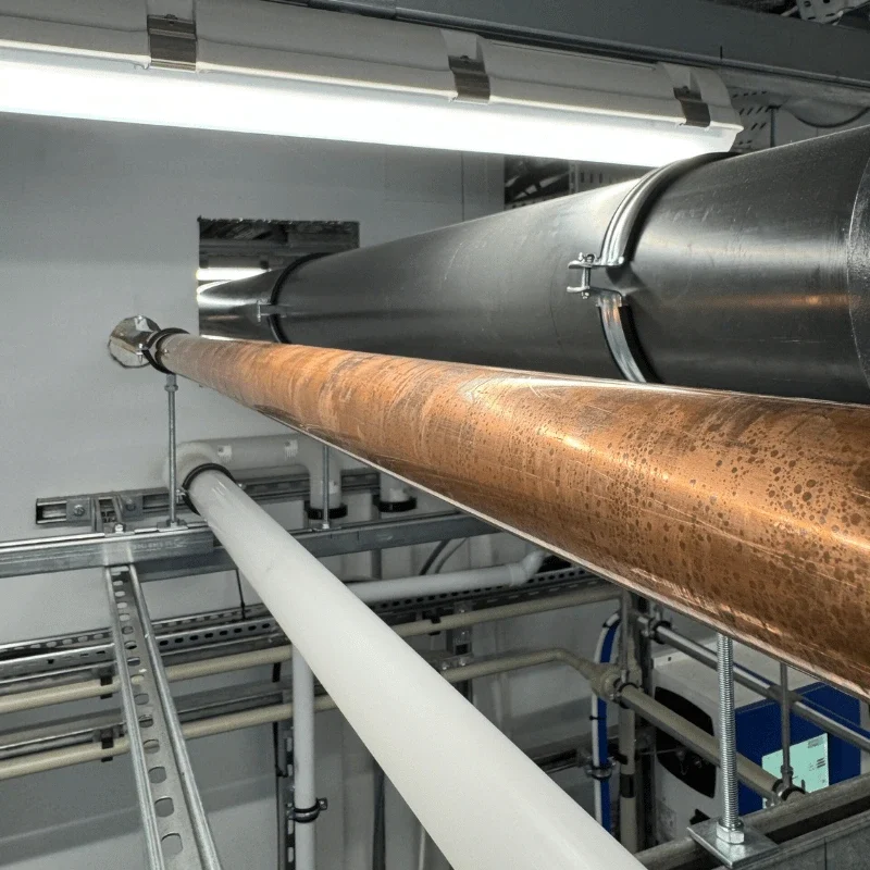 Large-bore copper hot water pipework and dual containment system installed overhead in a research laboratory in Towcester.